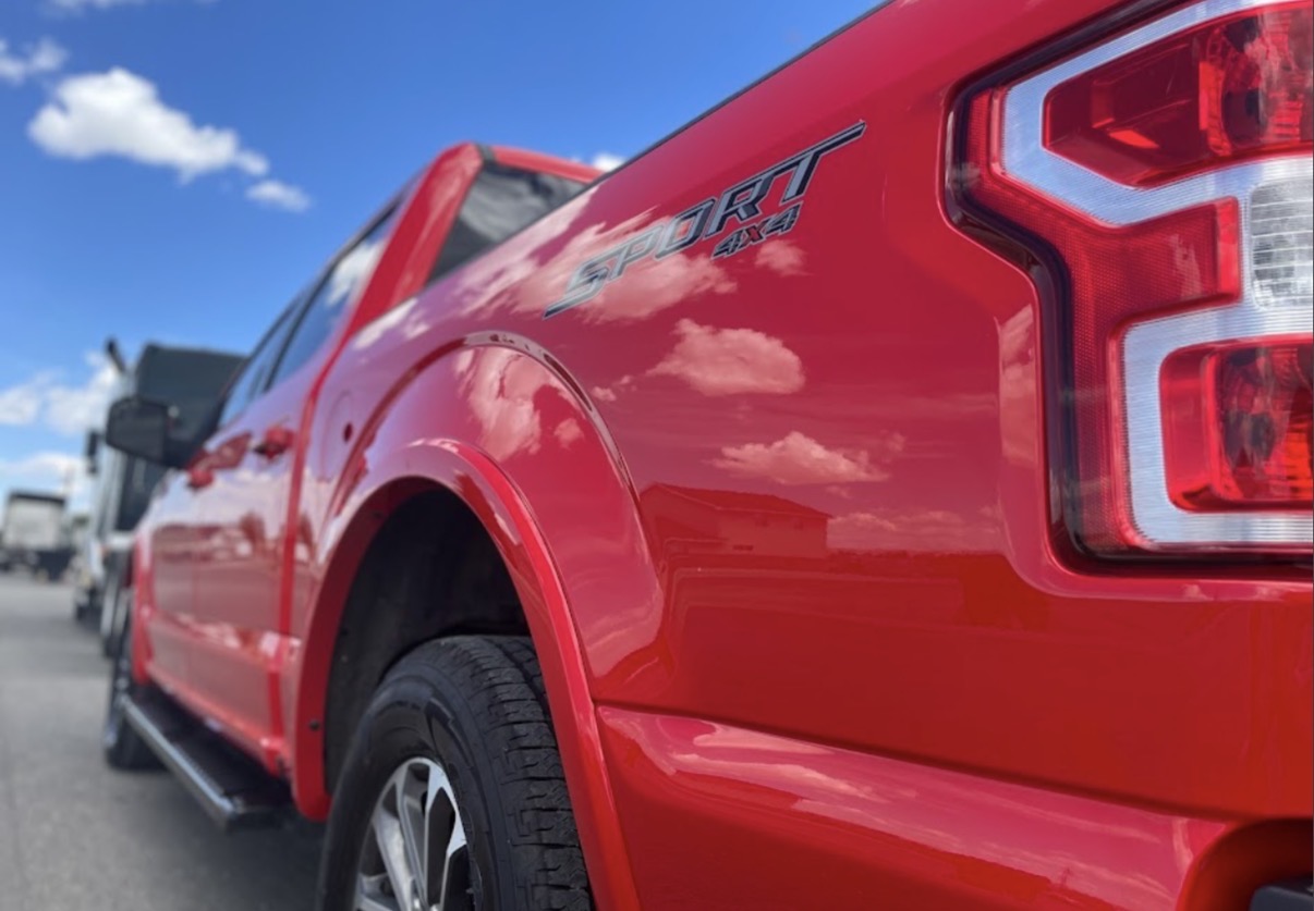 Red Ford F-150 Sport 4x4 bedside reflecting clouds after ceramic coating