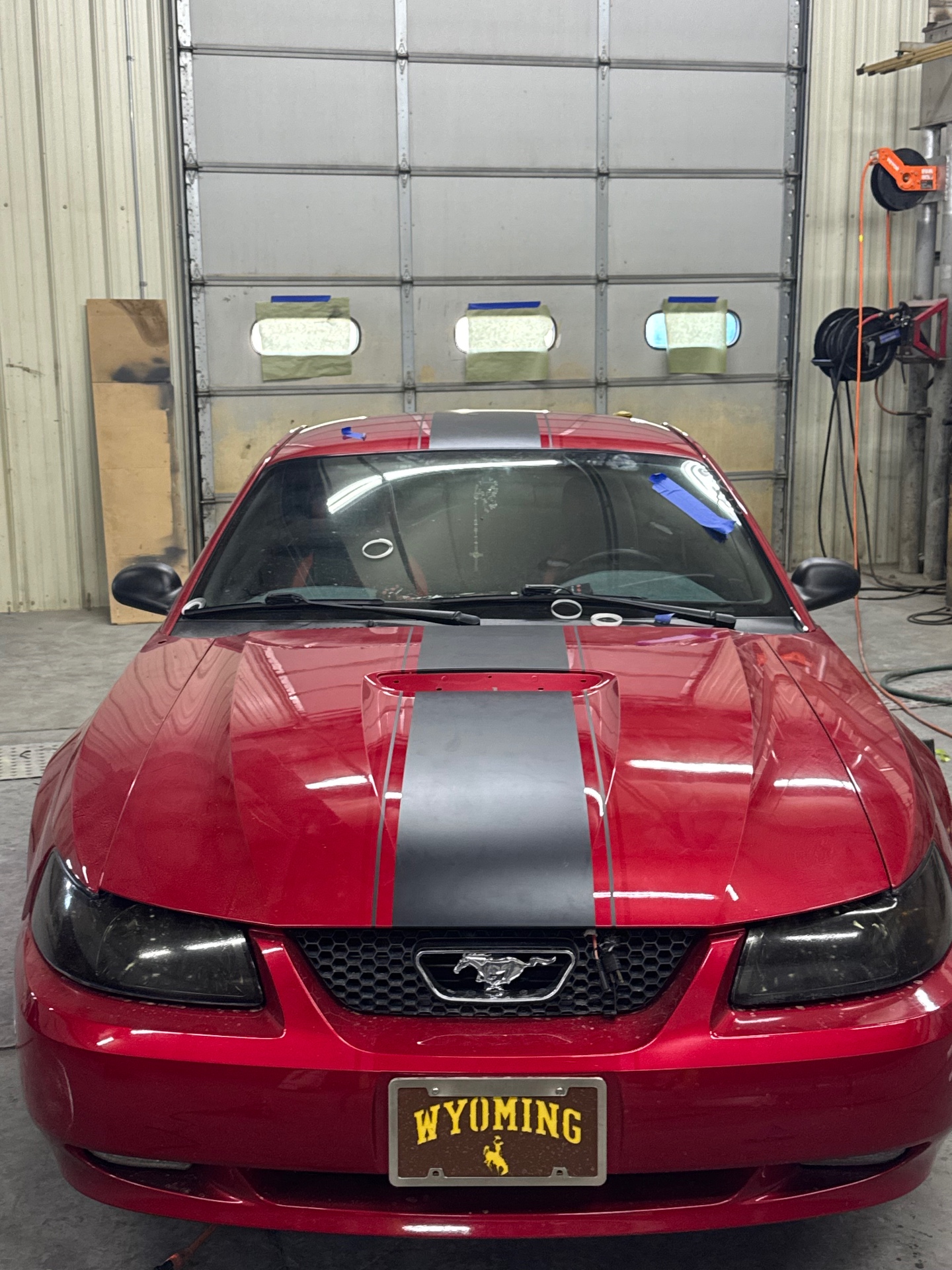 Red Ford Mustang with matte black dual racing stripes